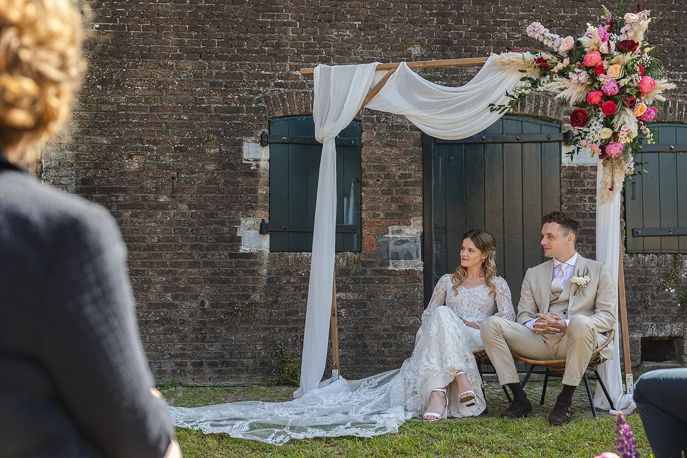 Bruidspaar onder een backdrop met doeken en bloemen