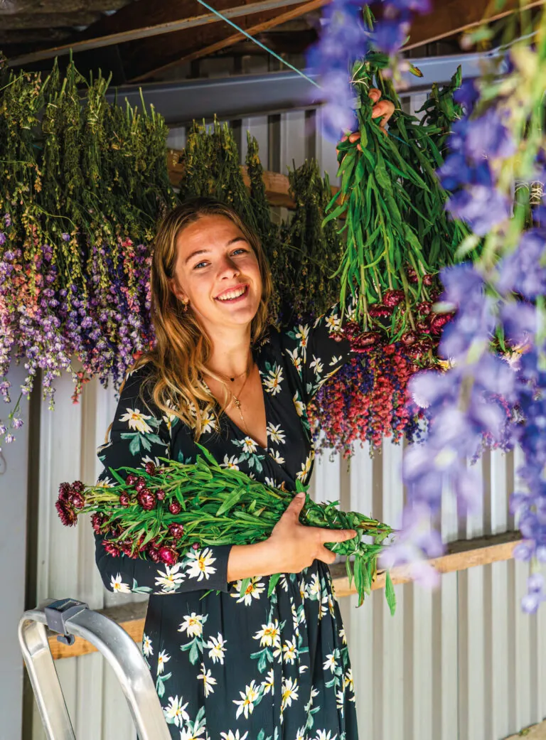 Celine met een bos verse bloemen tussen de hangende droogbloemen