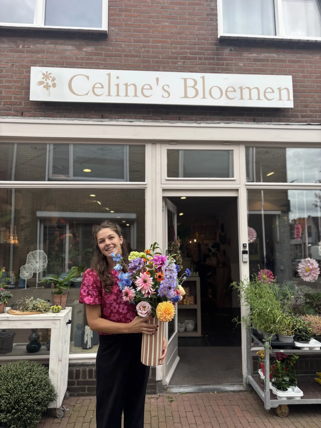 Celine met een grote bos bloemen voor haar winkel aan de Langstraat in Arnemuiden