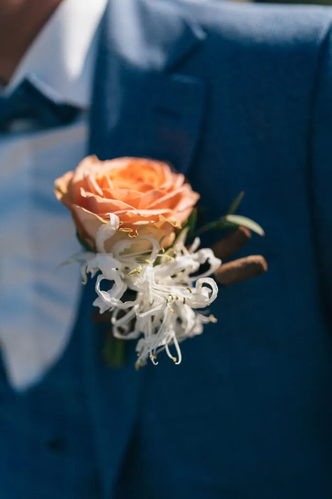 Corsage met een perzikkleurige roos op een blauw pak