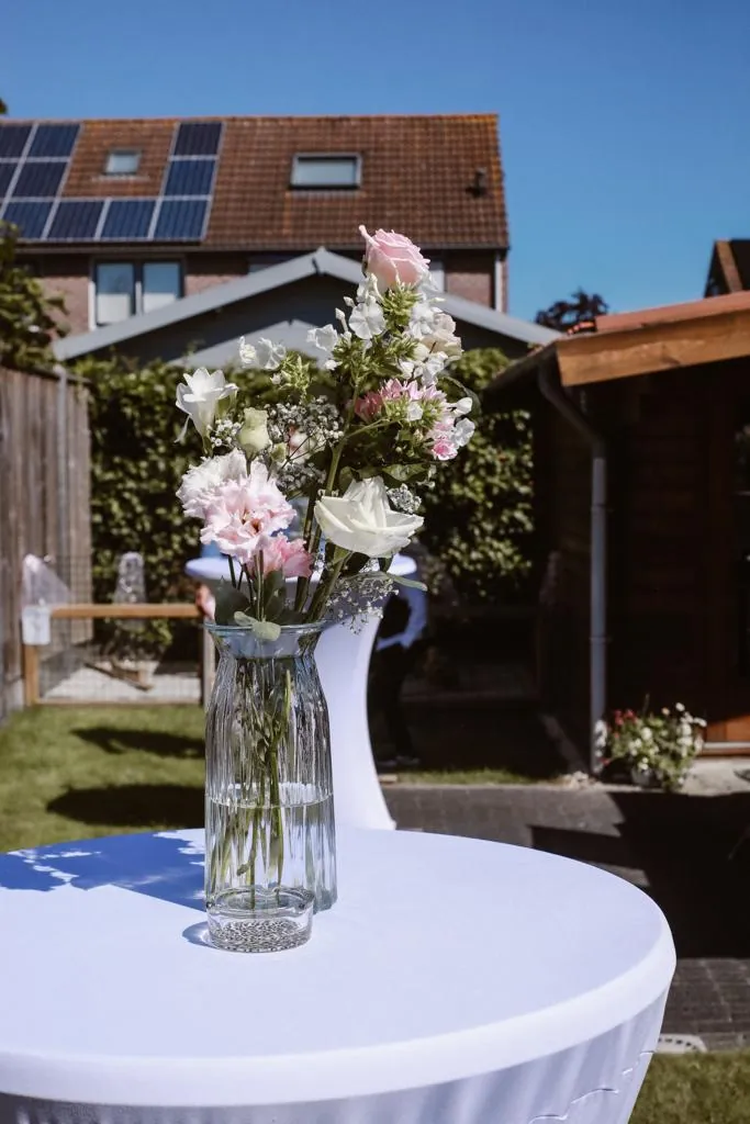 Een vaas met verse bloemen op een gedekte tafel in de tuin